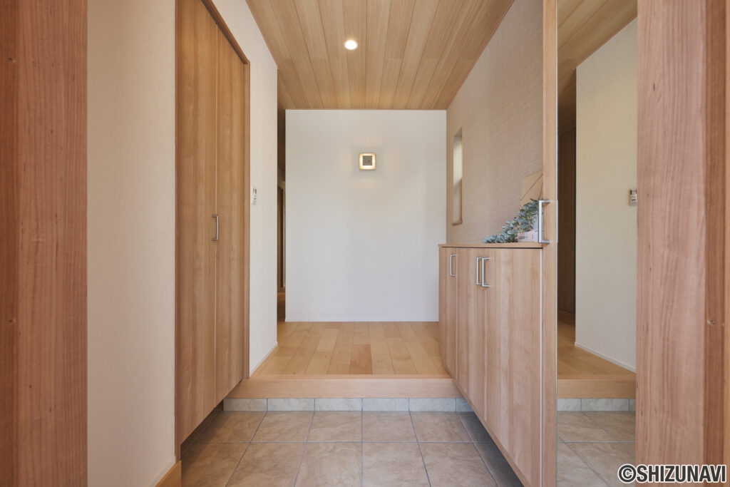 やさしい木目に迎えられる、温もりあふれる玄関ホール。天井・建具・下足収納すべてが木目で統一されたやさしい空間。素材の色合いはナチュラルトーンで揃えられており、明るく柔らかな印象を与える玄関デザイン。