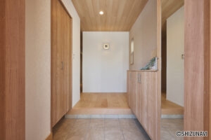 やさしい木目に迎えられる、温もりあふれる玄関ホール。天井・建具・下足収納すべてが木目で統一されたやさしい空間。素材の色合いはナチュラルトーンで揃えられており、明るく柔らかな印象を与える玄関デザイン。