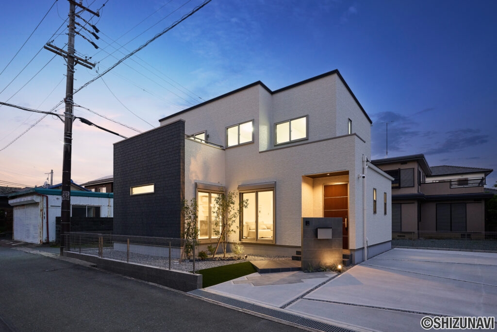 白とダークグレーのサイディングが照明に照らされ、陰影のある立体感を演出。門柱やアプローチにも照明を配し、植栽の緑がさりげなくライトアップされることで、上質で温もりある雰囲気に包まれます。シンプルなデザインの中に洗練と優しさが調和した、帰るたびに心が満たされる一邸です。