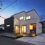 白とダークグレーのサイディングが照明に照らされ、陰影のある立体感を演出。門柱やアプローチにも照明を配し、植栽の緑がさりげなくライトアップされることで、上質で温もりある雰囲気に包まれます。シンプルなデザインの中に洗練と優しさが調和した、帰るたびに心が満たされる一邸です。