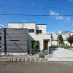 白とダークグレーのサイディングを組み合わせた、スタイリッシュで印象的な外観デザイン。南道路に面しており、日当たりの良さと開放感を感じられます。直線的なフォルムと異素材のコントラストが美しく、モダンな佇まいの中に上質な落ち着きを演出。