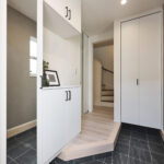 玄関ドアを開けると、明るく開放的な玄関ホールが迎えてくれます。白を基調としたシューズボックスと建具が空間を広く見せ、グレーのタイルと壁面が落ち着いた印象をプラス。