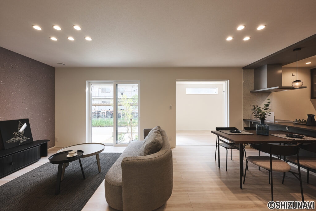 南向きの大きな窓から光がたっぷりと差し込む、明るく心地よいLDK。シンプルモダンを基調に、温かみのある木目フロアと落ち着いたトーンのアクセントクロスが空間に上品さを添えます。