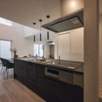 【B棟】ブラックで統一したキッチンが空間を引き締める、洗練されたLDK。吹き抜けからの光が、上質で落ち着きのある雰囲気を演出します。