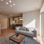 【C棟】木の温もりとグレイッシュカラーが調和した上質空間。キッチンから見守れる和室は、子育てにも来客にも便利。