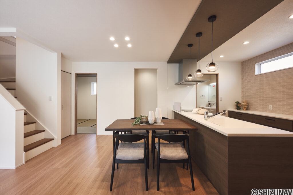 【C棟】デザイン性と使いやすさを両立したキッチン・ダイニング。落ち着いた木目と照明が上質な時間を演出。家族の会話が自然と生まれる空間。