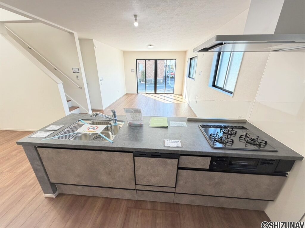 １号棟　キッチン３口のガスコンロ・グリル・食洗器付きのキッチン。目線がすっきりしてますので、開放感◎調味料の小物なども収納できるスペースあり。収納力も高いです。コンロの横の壁は、掃除しやすい素材という気遣いもうれしいですね。
