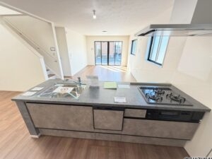 １号棟　キッチン３口のガスコンロ・グリル・食洗器付きのキッチン。目線がすっきりしてますので、開放感◎調味料の小物なども収納できるスペースあり。収納力も高いです。コンロの横の壁は、掃除しやすい素材という気遣いもうれしいですね。