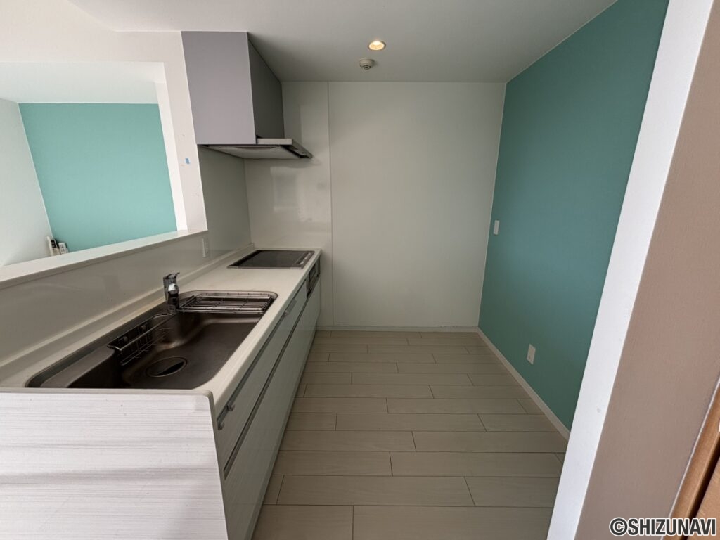 キッチンの別角度のお写真です。スペースが広く、後ろの水色の壁紙がアクセントになっております。