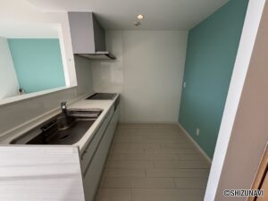 キッチンの別角度のお写真です。スペースが広く、後ろの水色の壁紙がアクセントになっております。